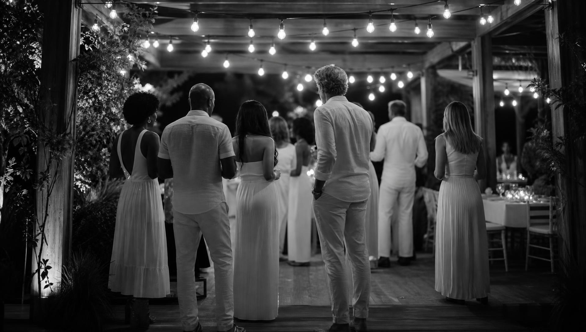 Guests in white attire at a past all-white celebration surrounded by white florals and candlelight